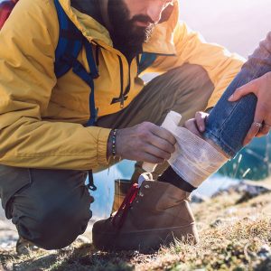 CERTIFIED WILDERNESS FIRST RESPONDERS Guide helps someone with a sprained ankle.