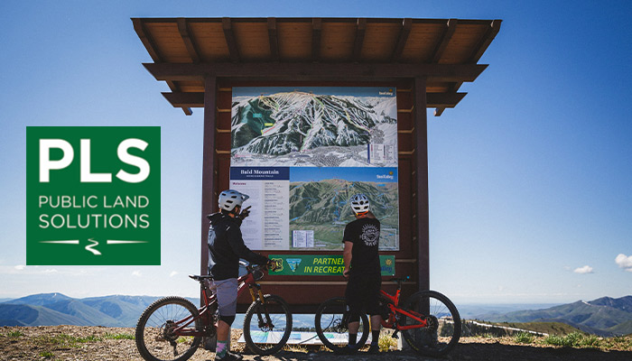 plsImage Riders at a trailhead sign.